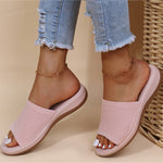Pink open-toe sandals worn with light blue jeans on a beige background