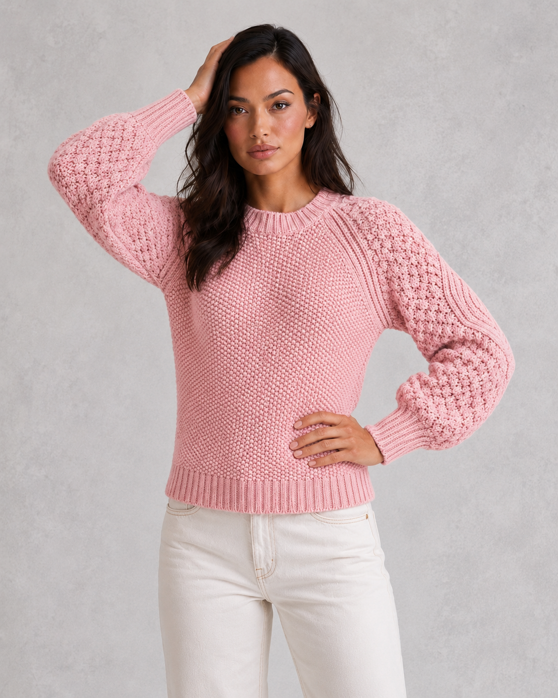 Woman wearing a pink knitted sweater against a gray background