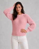 Woman wearing a pink knitted sweater against a gray background