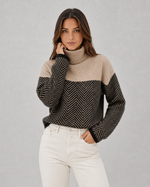 Woman wearing a two-tone sweater with a plain background