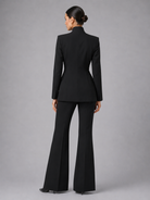 Woman wearing a black suit with flared pants on a gray background