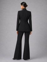 Woman wearing a black suit with flared pants on a gray background