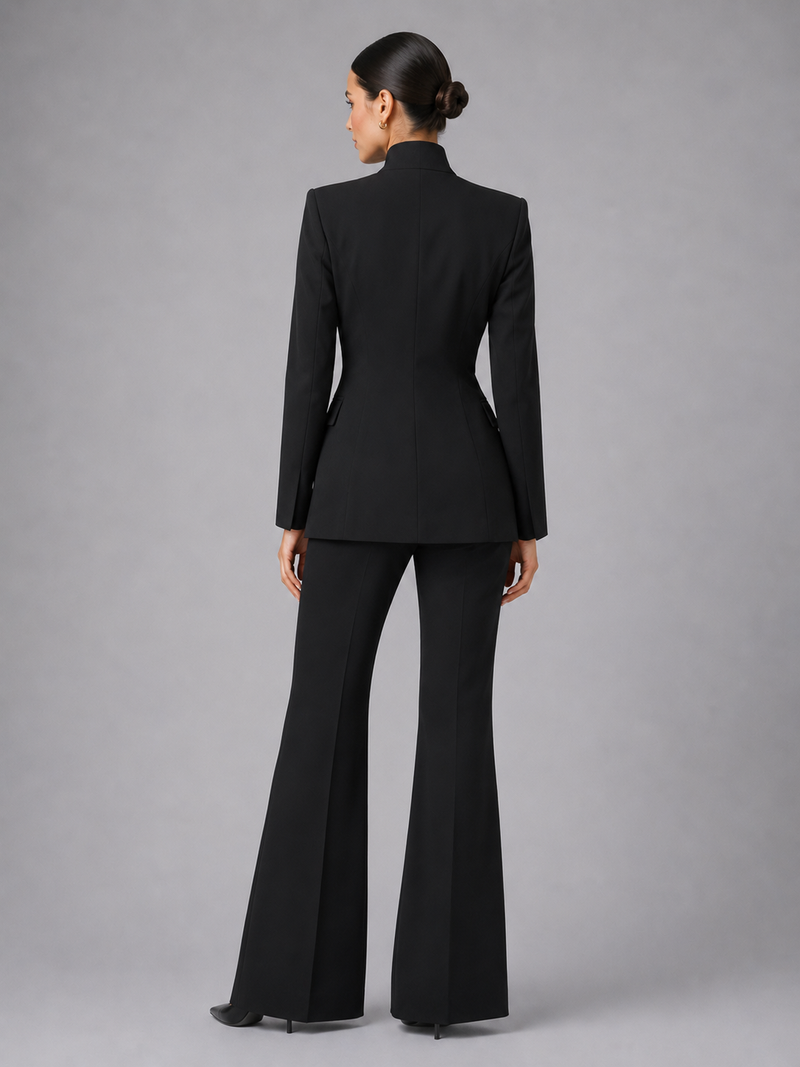 Woman wearing a black suit with flared pants on a gray background