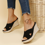 Black wedge sandals worn with denim jeans on a beige background