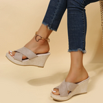 Wedges worn with rolled-up jeans on a beige background