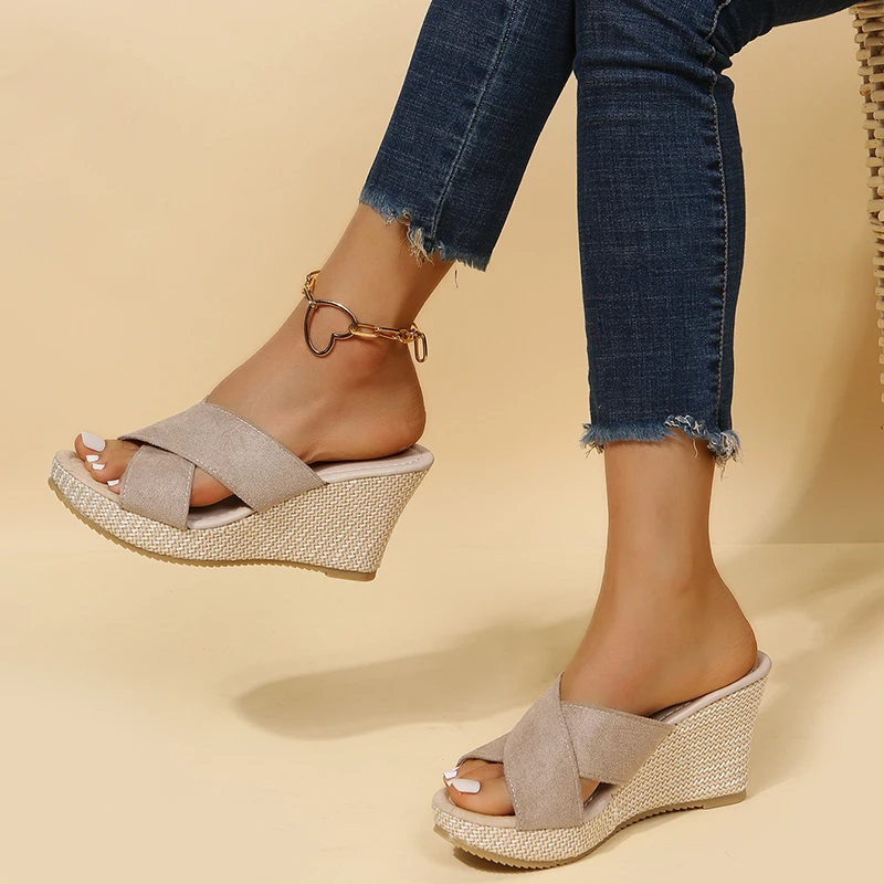Wedges worn with rolled-up jeans on a beige background
