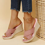 Pink wedge sandals worn with denim jeans on a beige background