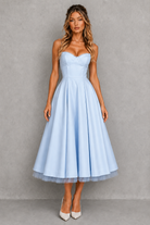 Woman wearing a light blue strapless dress against a gray background