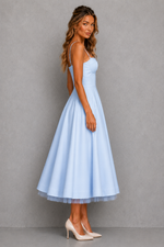 Woman wearing a light blue dress against a gray background