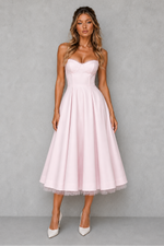 Woman wearing a pink strapless dress against a gray background