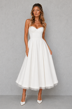 Woman wearing a white strapless dress against a gray background