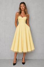 Woman wearing a yellow dress against a gray background