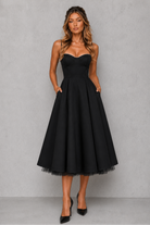 Woman wearing a black dress against a gray background