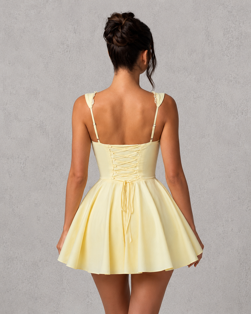 Woman wearing a yellow dress with thin straps against a gray background