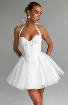 White halter-neck dress with a bow detail on a gray background
