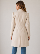 Woman wearing a beige coat on a plain background