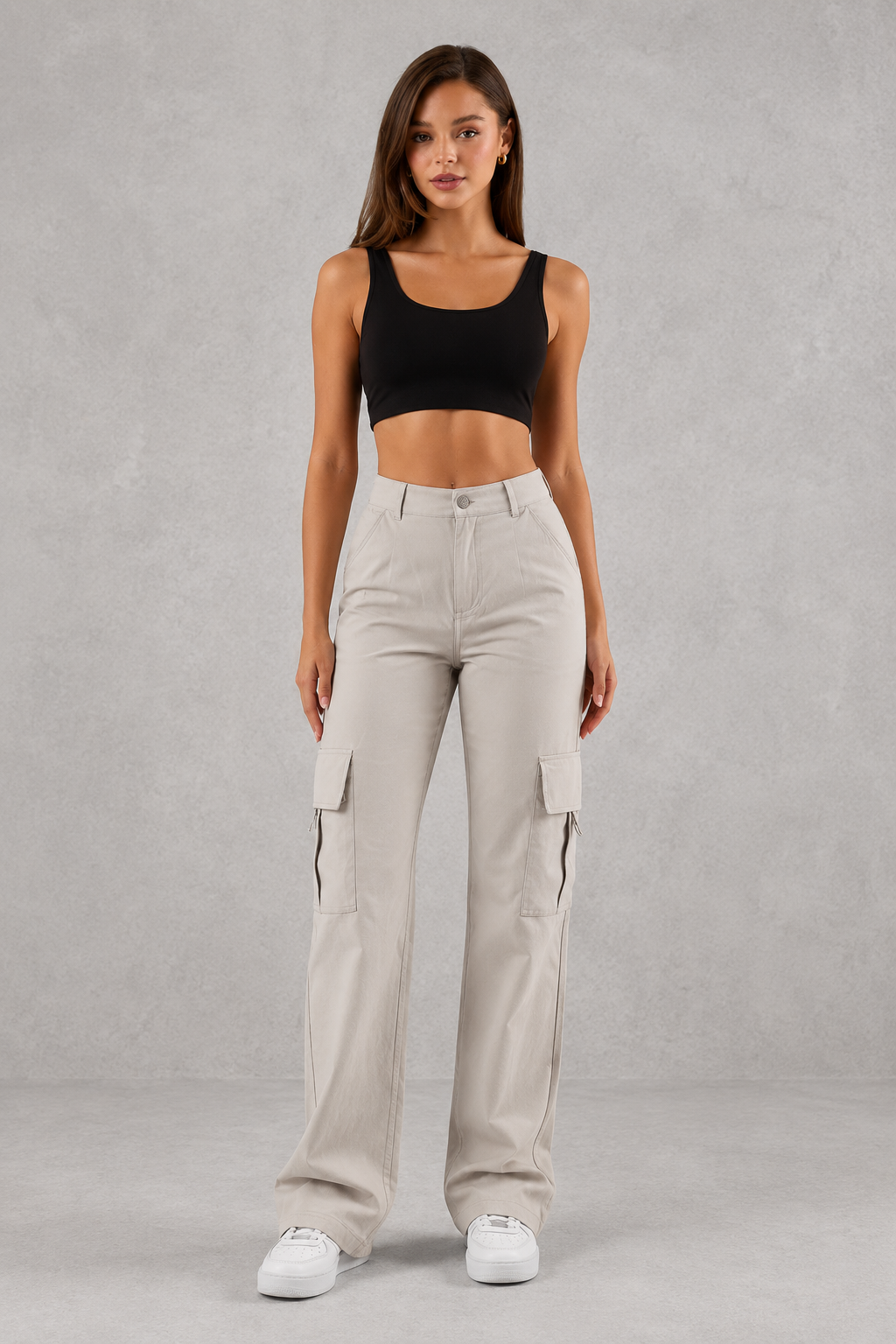 Woman wearing beige cargo pants and a black top on a gray background