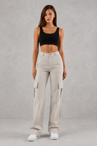 Woman wearing beige cargo pants and a black top on a gray background
