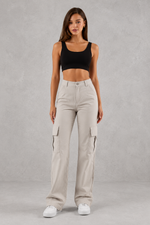 Woman wearing beige cargo pants and a black top on a gray background