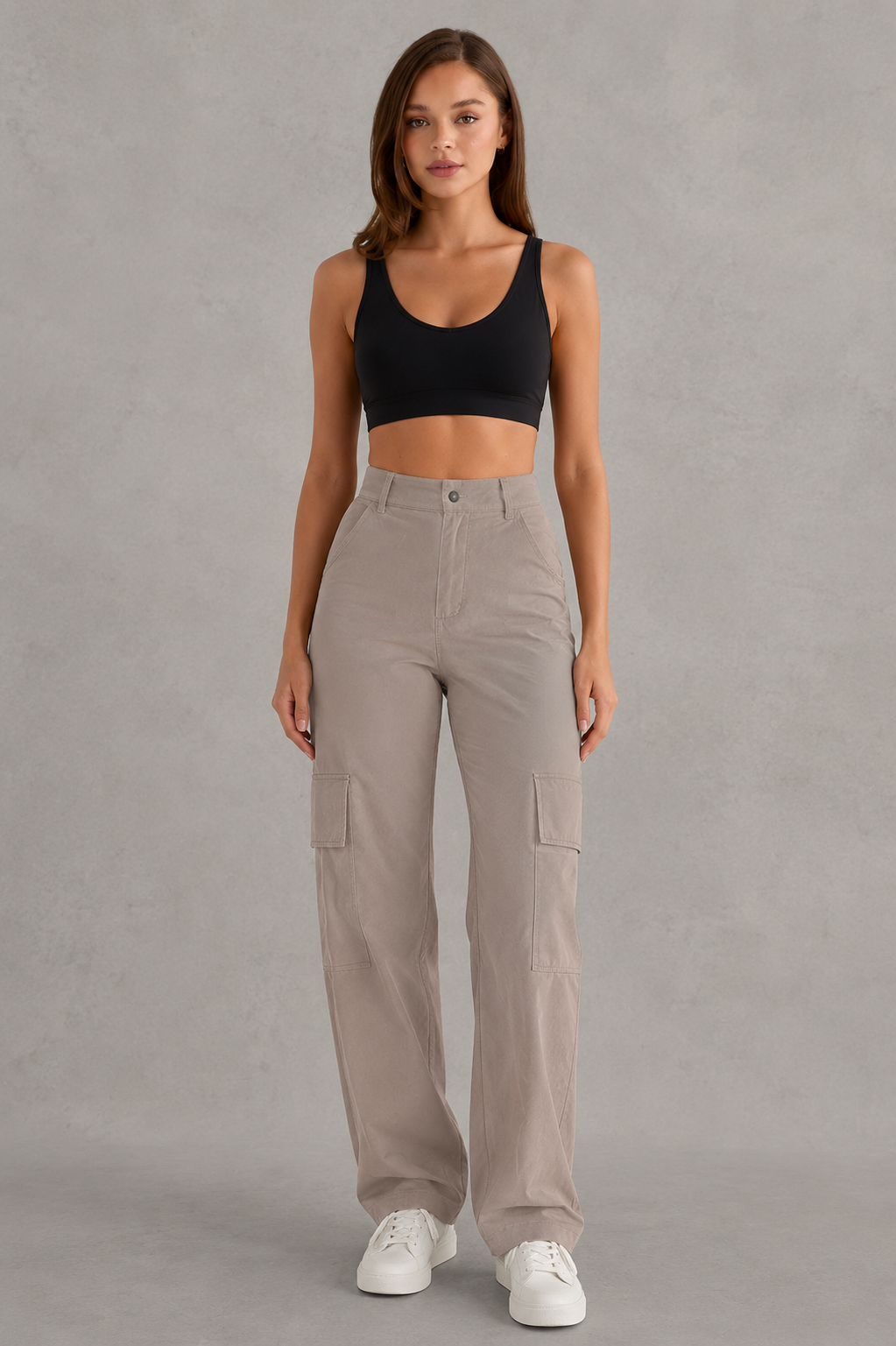 Woman wearing beige cargo pants and a black top on a gray background