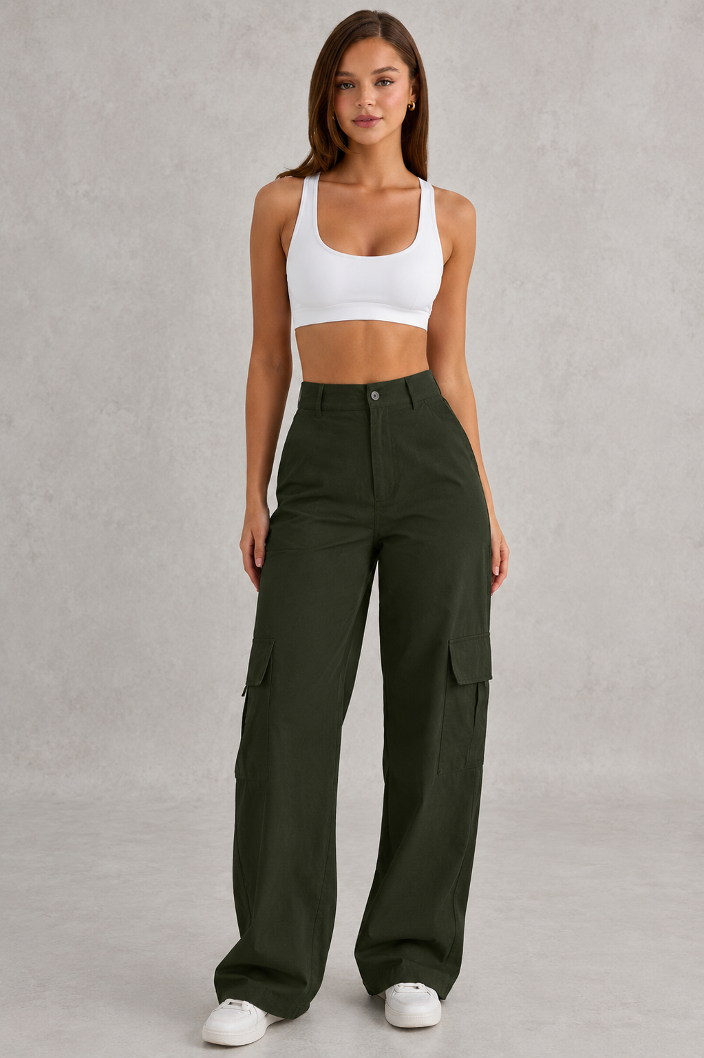 Woman wearing a white sports bra and green cargo pants on a gray background