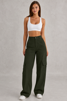 Woman wearing a white sports bra and green cargo pants on a gray background