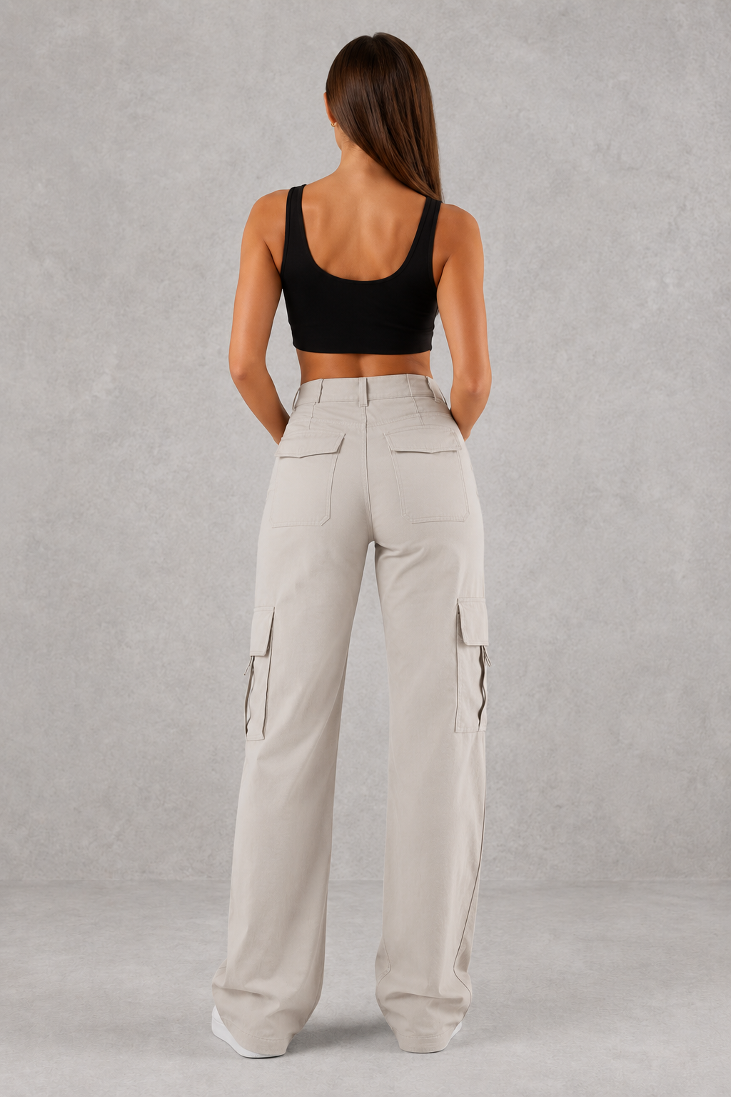 Woman wearing beige cargo pants and black top on a gray background