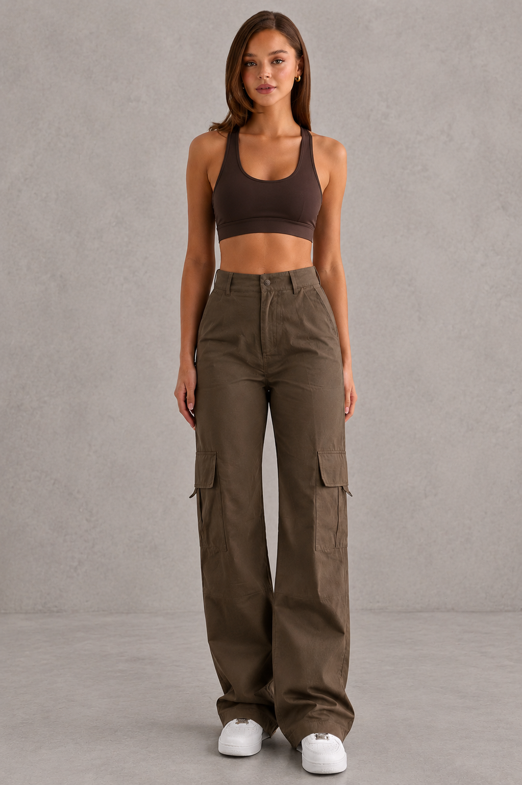 Woman wearing a brown sports bra and cargo pants against a gray background
