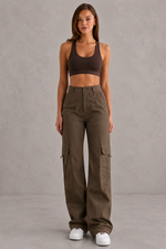 Woman wearing a brown sports bra and cargo pants against a gray background