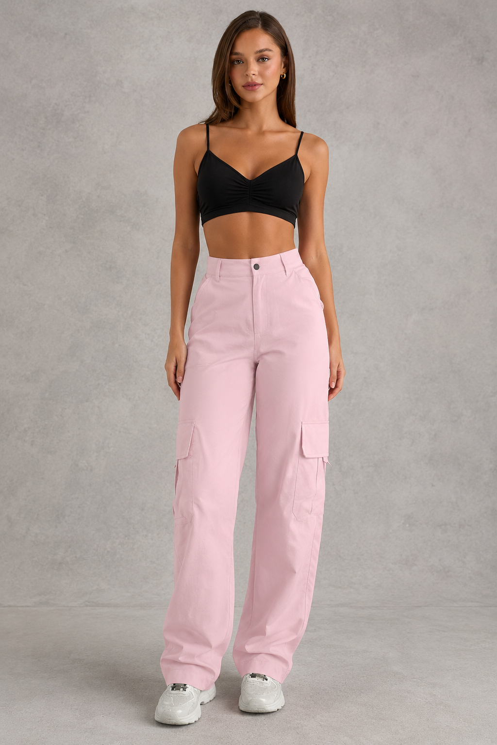 Woman wearing a black crop top and pink cargo pants on a gray background