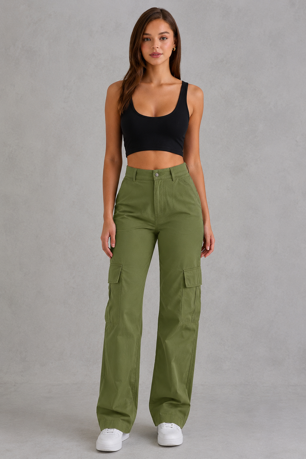 Woman wearing green cargo pants and a black top on a gray background