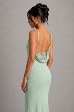 Woman wearing a mint green evening gown with a lace bodice on a gray background