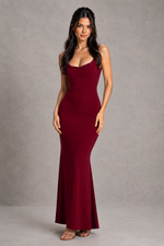 Woman wearing a burgundy evening gown against a gray background