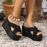 Black platform sandals worn on feet with pebbles and plants in the background