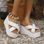 White wedge sandals worn on feet with a casual outdoor setting