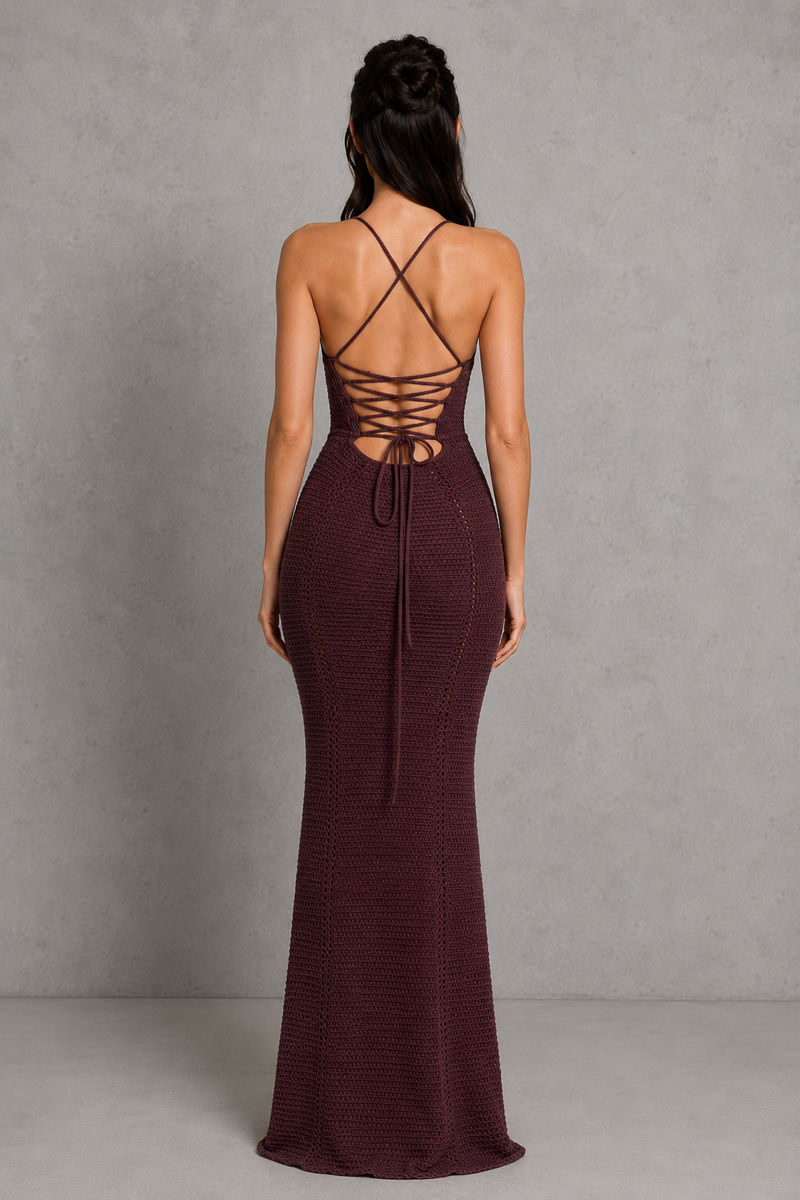 Woman wearing a burgundy evening gown with a lace-up back against a gray background