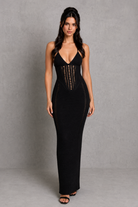Woman wearing a black dress with cut-out details against a gray background