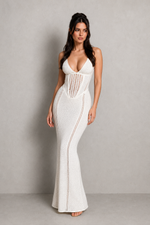 Woman wearing a white evening gown with intricate detailing against a plain background