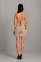Woman wearing a beige crochet dress with a neutral background