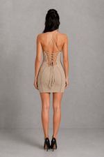 Woman wearing a beige crochet dress with a neutral background