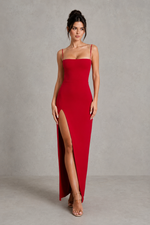 Woman wearing a red dress with a slit on a gray background