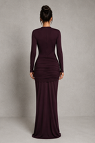 Woman wearing a long burgundy dress against a plain background