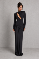 Woman wearing a black evening gown with a deep neckline against a gray background