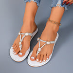 White sandals with embellishments worn by a person on a gray background