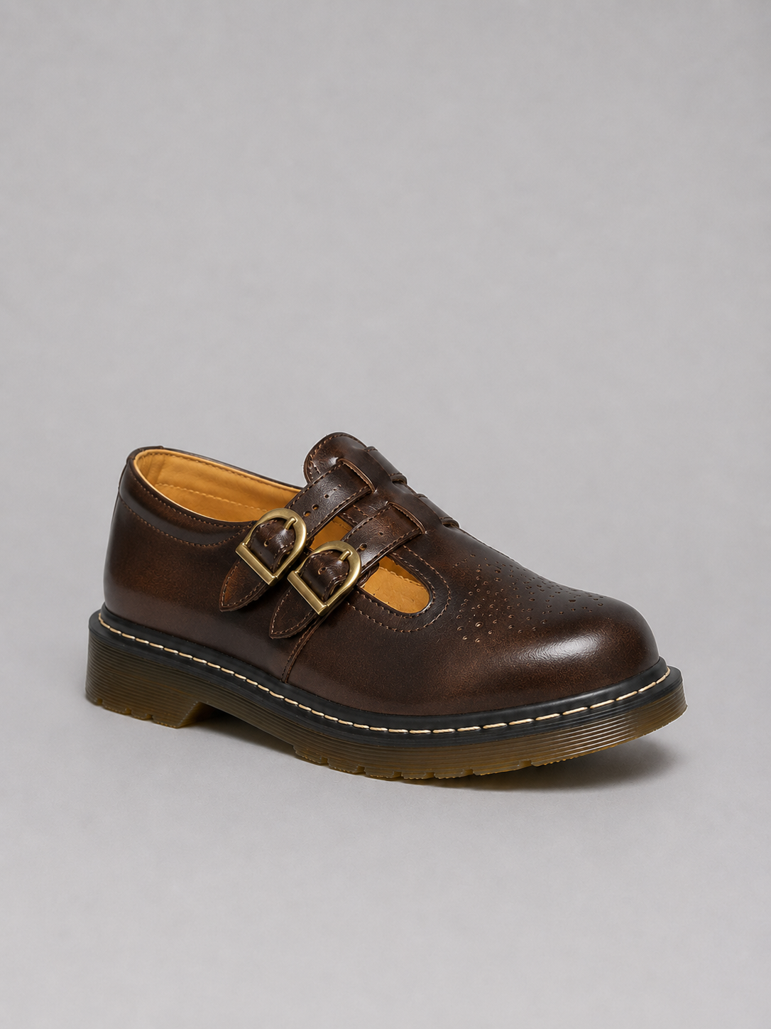 Brown leather shoe with buckles on a gray background