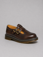 Brown leather shoe with buckles on a gray background