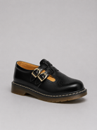 Black leather shoe with gold buckles on a gray background