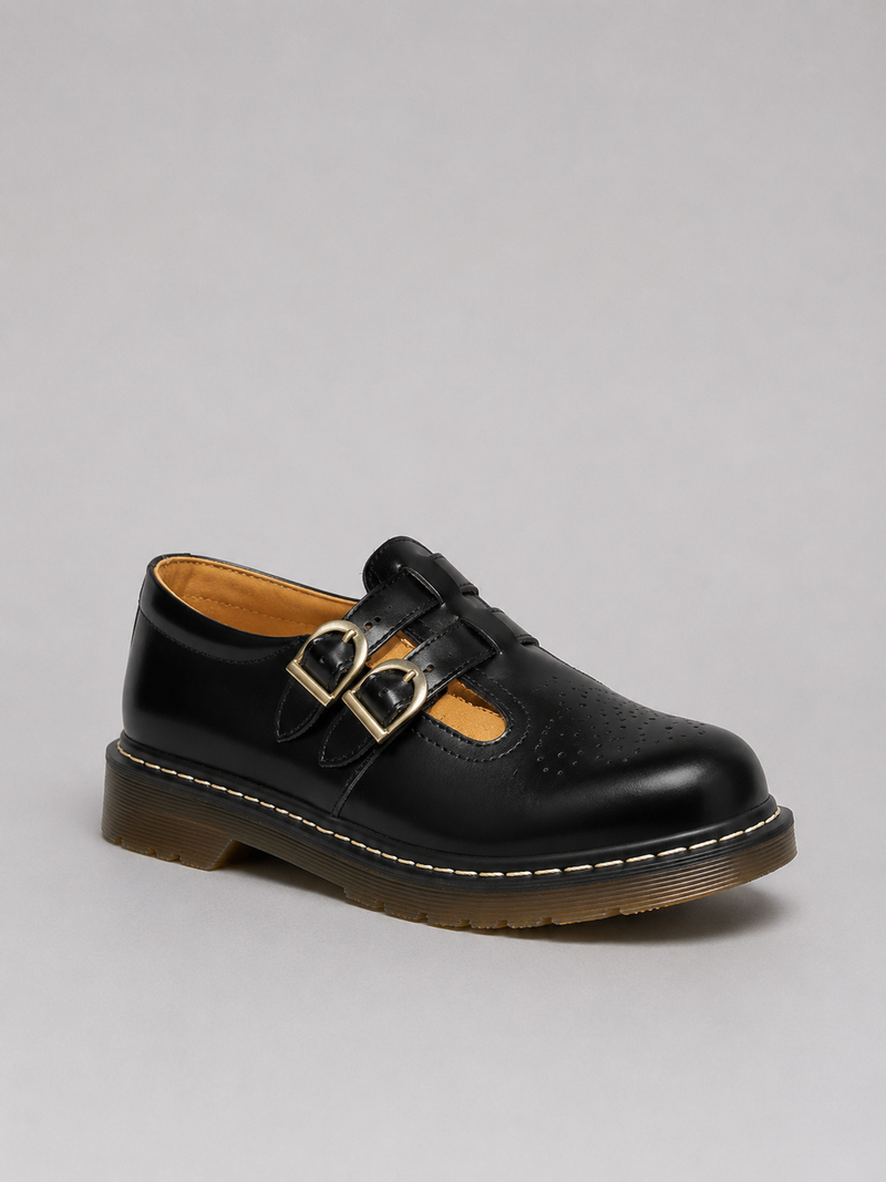Black leather shoe with gold buckles on a gray background