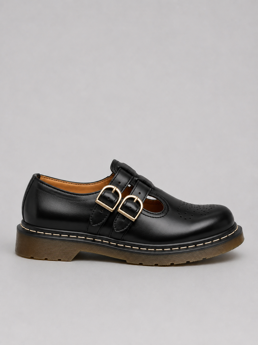 Black leather shoe with gold buckle on a gray background