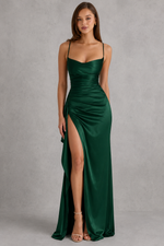 Woman wearing a green evening gown with a high slit on a gray background